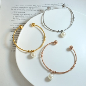 Minimalist open bangles in gold silver and rose gold with faux pearl pendant on a plate