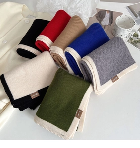 Flat lay of colorful knit scarves in black, red, and camel with contrast edge trims