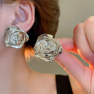 Dettaglio ravvicinato di orecchini a forma di rosa argento con petali testurizzati e finitura lucida
