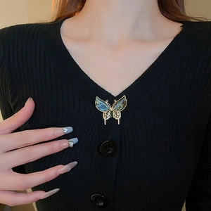 Détail d'une broche papillon dorée avec nacre colorée et pierre précieuse verte