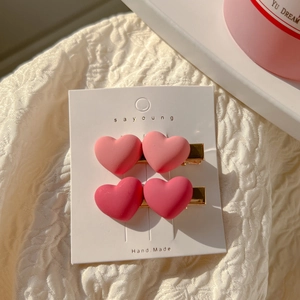 Close-up of pink gradient heart-shaped matte hair clips on a white display card