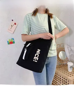 Detail view of black canvas crossbody bag with large NICE! text and buckle pocket design