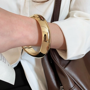Vue détaillée d'un bracelet manchette doré poli avec un design minimaliste effet miroir