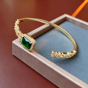 Detailed close-up of a gold emerald zircon bangle on a luxury jewelry gift box