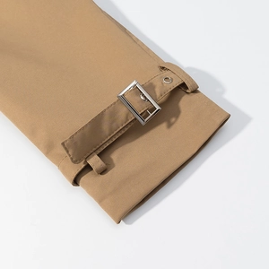 Detail of khaki trench coat cuff with metallic buckle strap and textured fabric finish