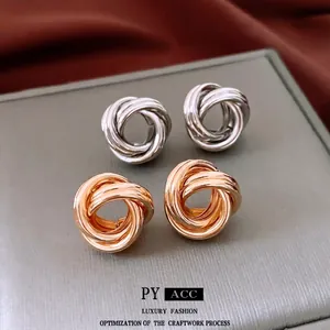Boucles d'oreilles nœud torsadé en argent et or sur présentoir de luxe