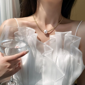 Close-up of elegant gold snake chain necklace with a large round white pearl pendant
