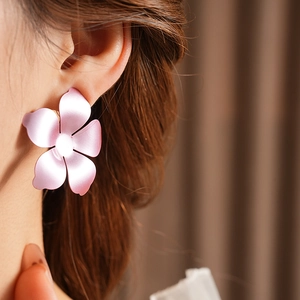 Gros plan de boucles d'oreilles fleurs rose mat avec dégradé portées par un mannequin