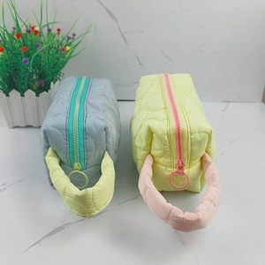 Quilted makeup bags in pastel blue and yellow with colorful zippers on marble