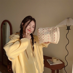 Floral quilted cosmetic bag held by model showing compact size and soft cotton texture