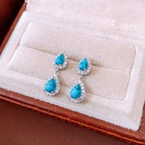 Macro shot of vintage silver teardrop turquoise earrings with cubic zirconia on velvet tray