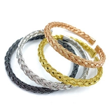 Close-up of four woven stainless steel bracelets in black, silver, gold, and rose gold finishes