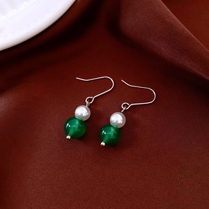 Vintage style silver hook earrings featuring white pearl and green bead on brown fabric