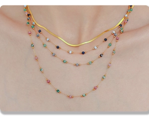 Detail of layered gold snake chain and colorful beaded necklaces on female model