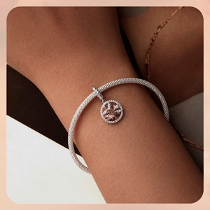 Close-up of rose gold tree of life charm on silver mesh bracelet with cubic zirconia
