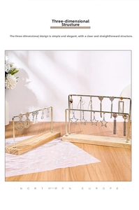 Detail of minimalist gold iron earring display stand with natural wooden base