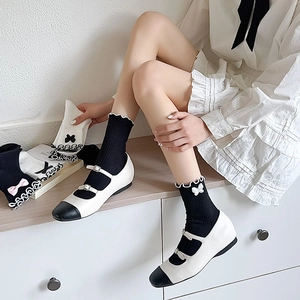 Detail of black mid-calf socks with white ruffled trim and decorative bows