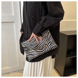Detail of zebra print envelope clutch bag with gold metallic trim and buckle closure