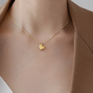 Elegante goldene Titanhalskette mit poliertem Herzanhänger an einem Model