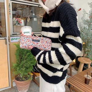 Floral corduroy makeup bag with black merciparis label held by a person in a cafe
