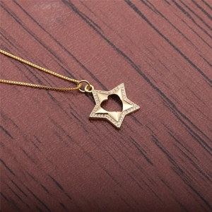Macro shot of gold star pendant with hollow heart and zircon on a wooden surface