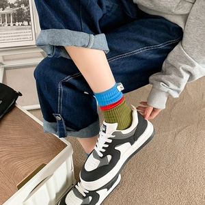 Detail of colorful striped crew socks with small fabric label and casual sneakers