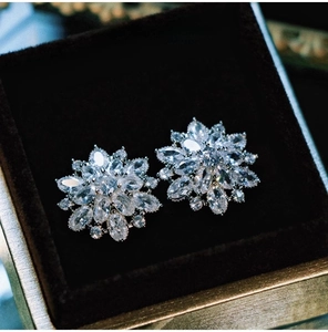 Macro shot of silver flower earrings with sparkling zircons in a brown jewelry box