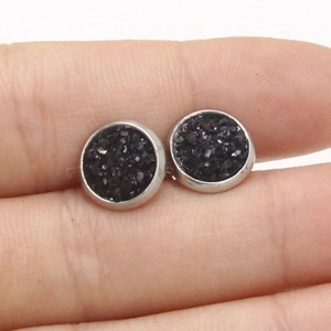 Detailed view of 8mm black star-dust earrings held in hand to show actual scale