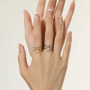 Close-up of stacked gold and silver heart rings with white zircon stones on fingers