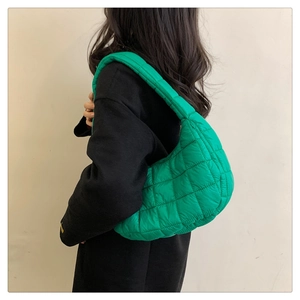 Detailed view of green quilted down shoulder bag on model with soft puffer texture