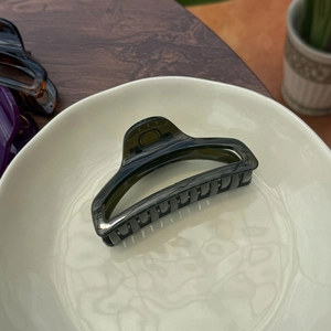 Detail of a 10cm dark green translucent resin hair claw clip on a ceramic tray