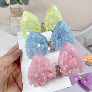 Close-up of three sparkling sequin bow clips for girls in yellow, blue, and pink colors