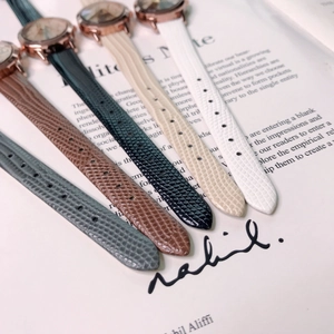 Close-up of five leather strap watches in various colors with rose gold cases on a magazine