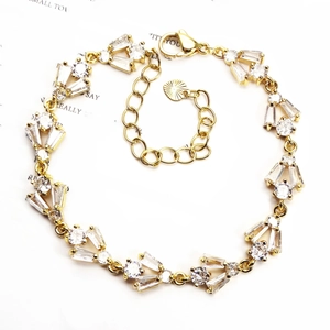 Detailed view of gold chain bracelet with zircon heart and clover charms and adjustable clasp