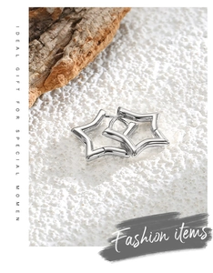 Detailed view of silver star earrings on white texture with natural wood background