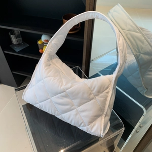 Detailed view of white quilted puffer bag displayed on a modern transparent stand