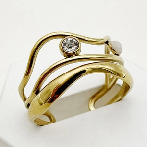 Macro shot of gold plated multi-layer wave ring with clear and white gemstones