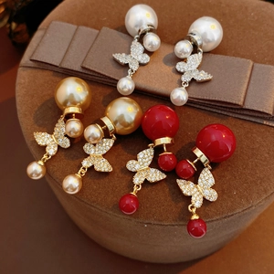 Detail of vintage butterfly pearl earrings in red, white and gold with cubic zirconia stones