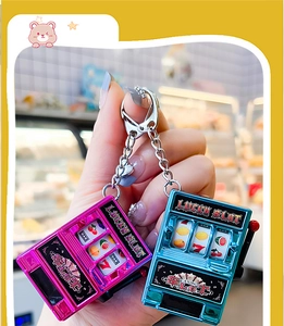 Close-up of pink and blue mini slot machine keychains with functional rotating levers