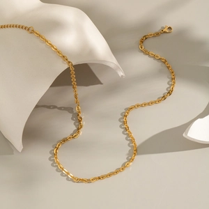 Collier à maillons dorés minimaliste avec fermoir mousqueton sur sculpture blanche