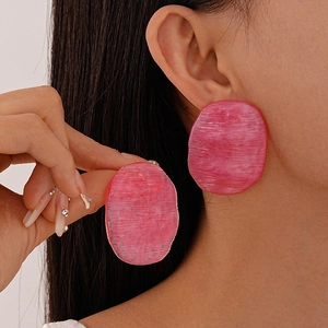 Pink oversized oval acrylic earrings with brushed texture shown on a female model