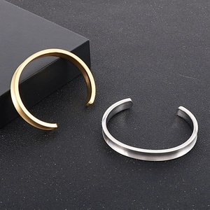 Detail of matte brushed stainless steel C-shape bangles in gold and silver finish