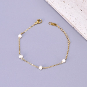 Macro shot of gold stainless steel bracelet with freshwater pearl and K18 hallmark tag