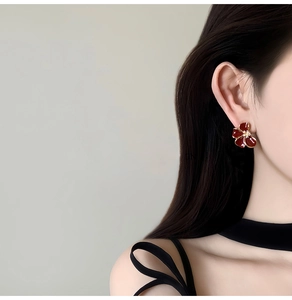 Gros plan d'une élégante boucle d'oreille fleur rouge foncé plaquée or 18 carats