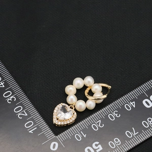 Elegant heart-shaped zircon earrings with white pearls and gold finish on a black background