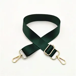 Detail of dark green nylon strap with textured weave and gold-tone metal hooks