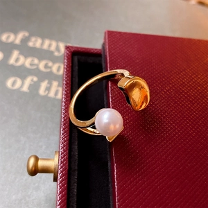 Detailed close-up of a gold open ring with a white pearl and cashew metal bead