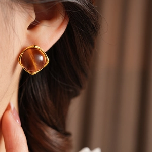 Gros plan d'une boucle d'oreille carrée dorée avec pierre en résine ambrée