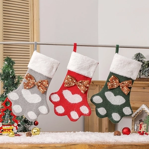 Trois chaussettes de Noël en forme de patte de chien en rouge, gris et vert tricoté