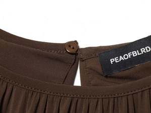 Detail of dark brown shirt neckline with pleated texture and button closure